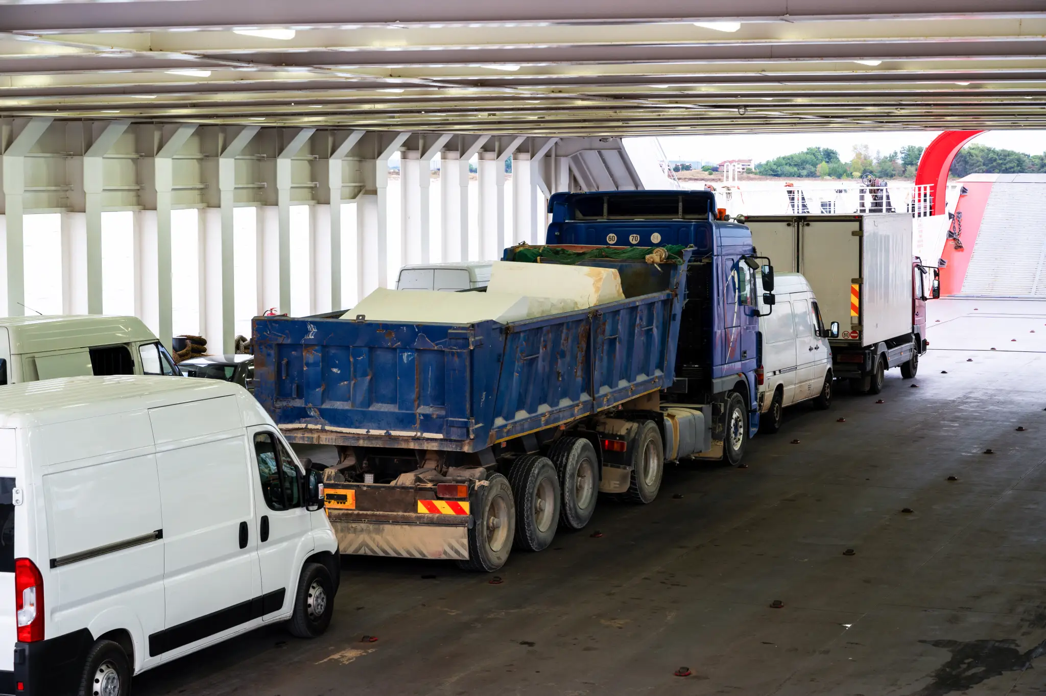 Trucks and vans parked inside a ferry cargo deck for transport across water