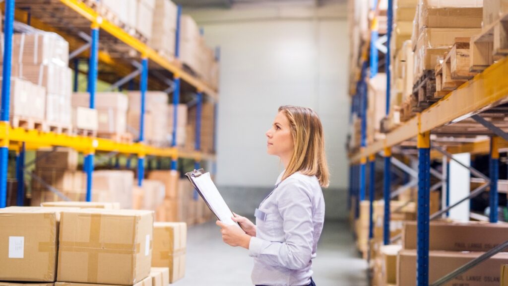 woman in a warehouse holds a clipboard