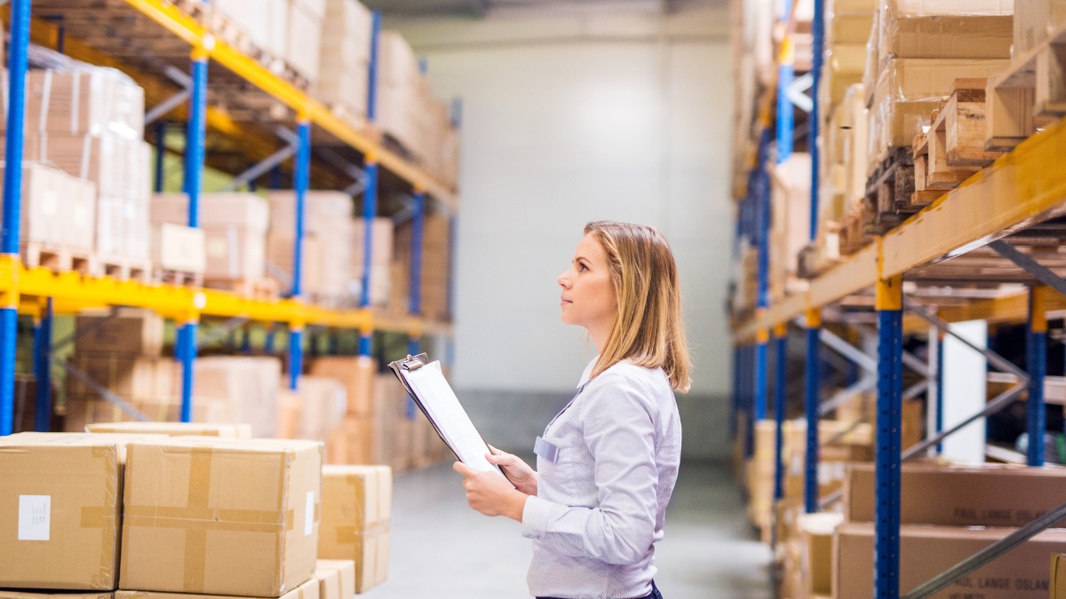 woman in a warehouse holds a clipboard