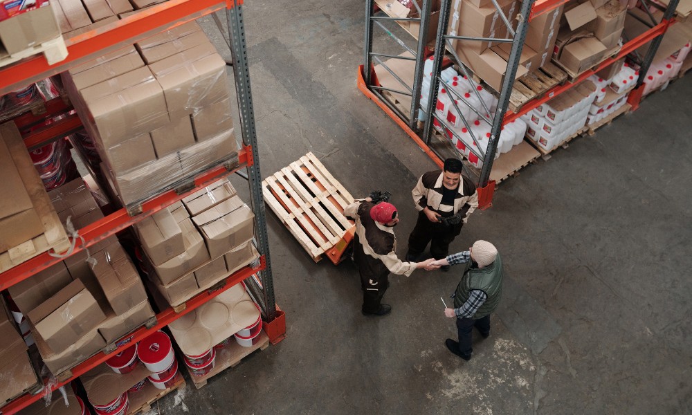 An overhead, high-angle view of three warehouse workers conversing
