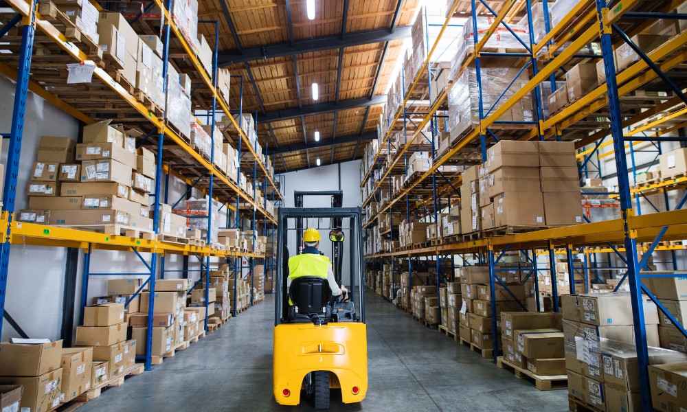 A warehouse worker wearing a yellow hard hat and a high-visibility safety vest