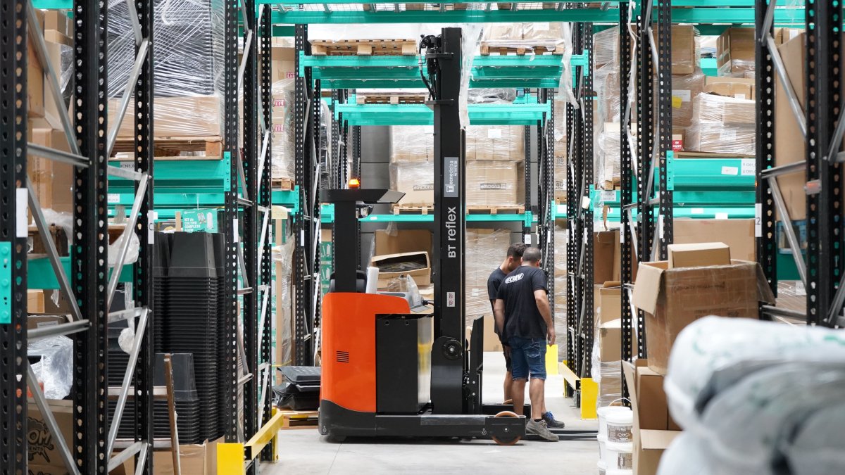 Warehouse workers and forklift moving through aisles managing logistics and inventory